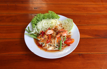 papaya salad with shrimp and vegetables, cabbage and yardlong bean in white dish on the wooden table.