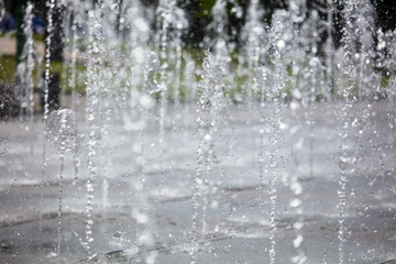 Plakat Splashing water from a fountain in the park as a background