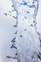 Splashing water with drops on the sky background