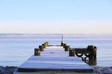 Lake jetty covered in frost on a cold sunny morning.
