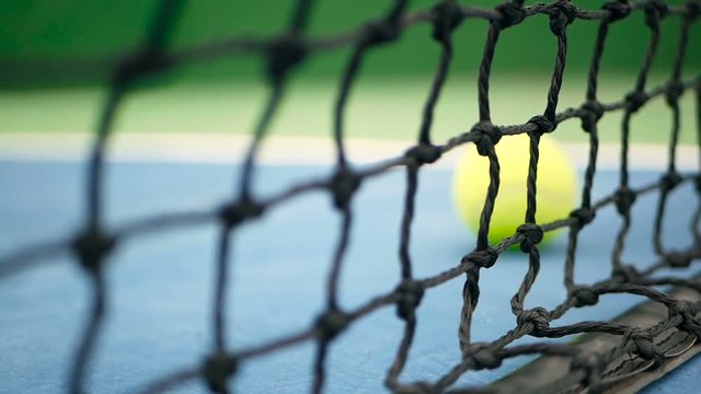 Close up of tennis equipment on the court. Sport, recreation concept. Yellow tennis balls hit the net on a clay green blue court next to the white line with copy space and soft focus