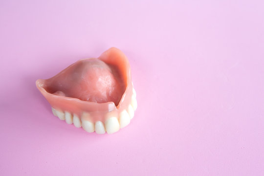 closeup of dental prosthesis on pink background