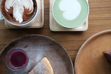 hot matcha green tea with heart latte art. cheese cake with berry syrup on wood tray