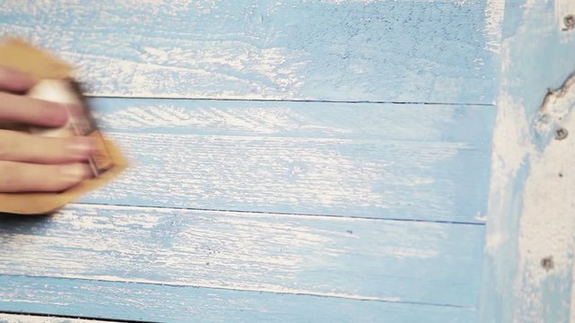 A blue wooden background is being polished with sandpaper