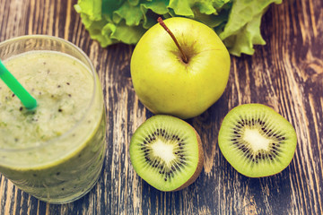 Healthy green smoothie with kiwi, apple on rustic wood background, top view