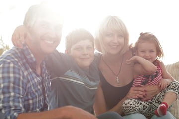 family with two children sitting together and looking at camera