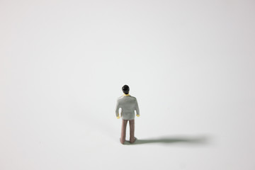 One miniature businessman on gray background top back view.
