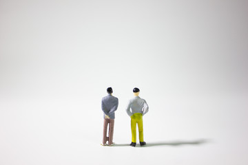 Two miniature businessman on gray background.