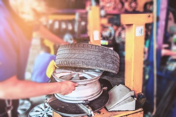 Technician repairing or changing car tire in car maintenance garage - people at car care maintenance service concept