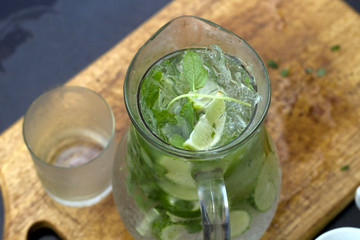 cold summer drink with lime and mint on a wooden board top view