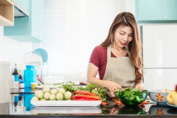 Young lady in modern bright kitchen prepare food with colorful vegetable - people and home doing cooking activity concept