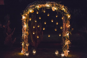 Night wedding ceremony, arch on party decorated with lights and candles in round glass spheres