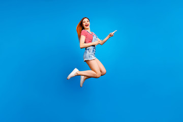 Full-size excited cheerful careless girl demonstrating empty place isolated on vivid blue background with copy space for text