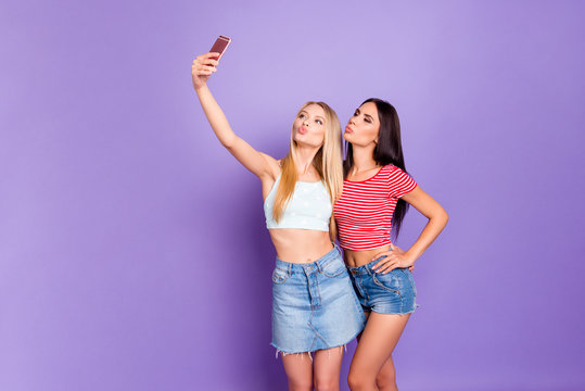 Portrait of lovely romantic girls shooting selfie on front camera sending kiss with pout lips using smart phone isolated on vivid violet background. Rest relax concept