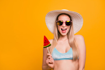 Close up portrait of young blond woman in white hat happy and joyful holds red sweets in hands...