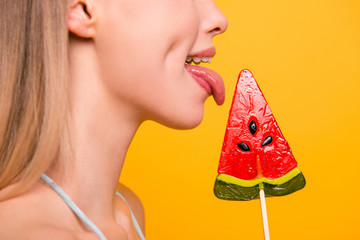 Crop portrait half-face in profile side girl licks caramel candy on a stick isolated on bright...