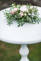 White wedding table decorated with green flowers arrangement, name cards, pink peony, white cutlery, rustic style