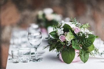 White wedding table decorated with green flowers arrangement, name cards, pink peony, white cutlery, rustic style