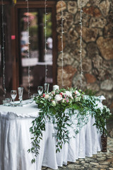 White wedding table decorated with green flowers arrangement, name cards, pink peony, white cutlery, rustic style
