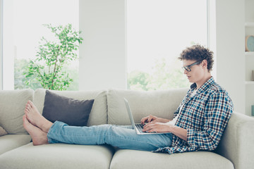 Handsome curly-haired serious young guy student, wearing casual, checkered shirt and jeans, sitting...