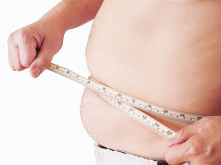 Fat man is measuring his belly using tape meter - dietary health concept