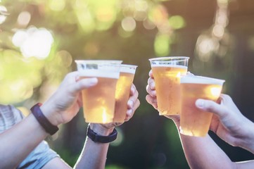 Celebration beer cheers concept - close up hands holding up glasses of beer of people group in...