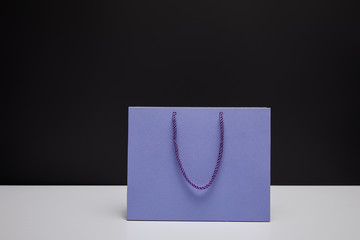 one violet shopping bag on white table isolated on black