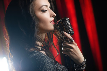 Portrait of beautiful woman singing in microphone