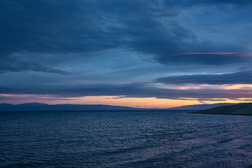 Scenic view of lake with mountains on horizon at sunset
