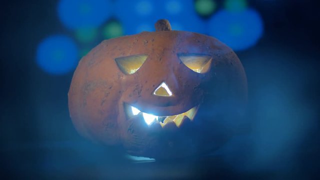Radiant jack-o-lantern located in a dark room with a party in it. Happy halloween pumpkin concept.