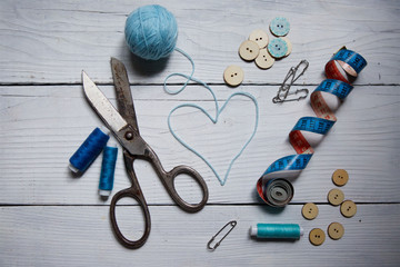 Various tools for sewing, hobby and creativity lie on the white wooden surface.