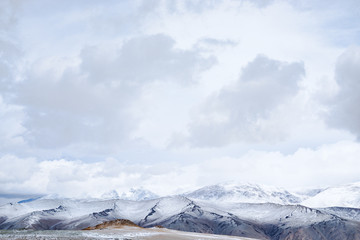 Panoramic view of snowy mountains under cloudy sky
