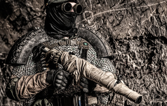 Post apocalyptic survivor, World War III soldier, global nuclear conflict partisan or stalker, in military cap and handmade body armor shooting with submachine gun wrapped in abandoned bunker or mine
