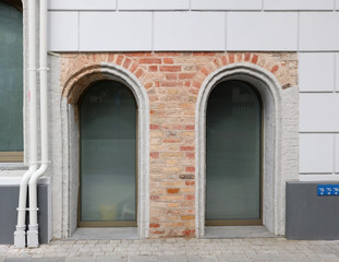 Two plastic arched windows in a brick wall of an old restored house