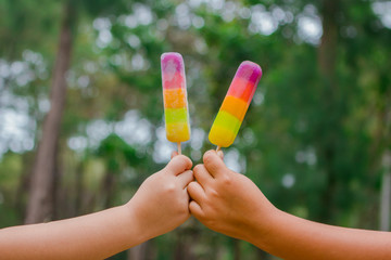 kids hands holding melting ice cream waffle cone in hands on summer light nature background