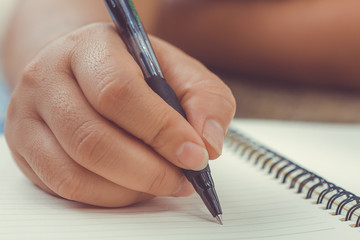 female hands with pen writing on notebook