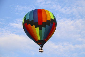 colorful hot air balloon against blue sky. hot air balloon is flying in white clouds. beautiful flying on hot air balloon