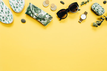Flat lay summer travel concept. Slippers, sunglasses, case, accessories on yellow background. Top view fashion background.