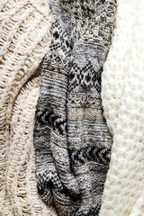 Bunch of knitted warm pastel color sweaters with different knitting patterns laid in messy pile, clearly visible texture. Stylish fall / winter season knitwear clothing. Close up, copy space for text.