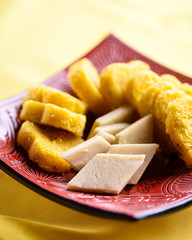 Barfi Indian sweets in a dish, with milk coconut barfi cut in diamond shape and heart shape saffron cardamom barfi.