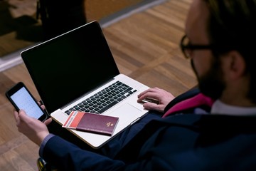 Businessman using mobile phone while working on laptop in