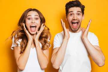 Photo of emotional couple man and woman in basic clothing screaming in surprise or delight and...