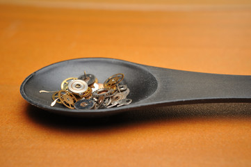 Detail of watch machinery in spoon on the brown wood background.