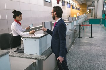 Airline check-in attendant handing digital tablet to commuter