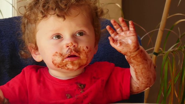 happy baby is eating a chocolate cake