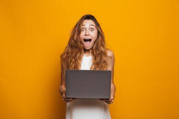 Portrait of a cheerful young girl holding laptop computer