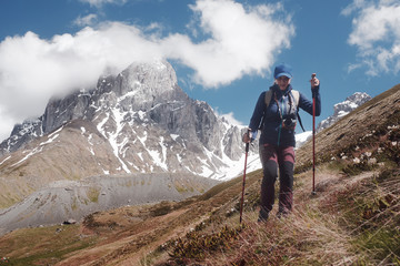 Happy hiker with trekking sticks walks and enjoys on the mountain trail. Travel sport lifestyle...