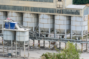 Big silos, belt conveyors and mining equipment in a quarry. Quarrying of stones for construction works. Mining industry in quarry.