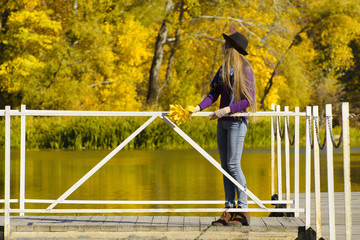 Girl in hat standing on the dock. Autumn, sunny.