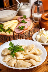 The concept of Ukrainian cuisine, vareniki with potatoes, with sour cream in a white plate on the table. breakfast in the restaurant. Copy space, selective focus